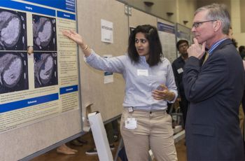 A student shows her poster to Scott Schroth, M.D.