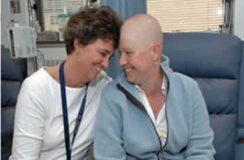 A cancer patient sitting and smiling with their doctor
