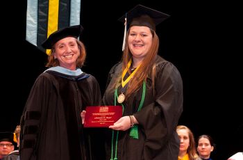A SMHS faculty member presents a graduating student with an honor 