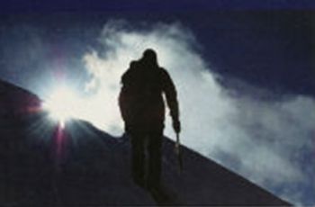 Silhouette of a mountain climber against a blue sky