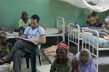 Dr. Amr Madkour sitting in a Nigerian medical clinic with several patients