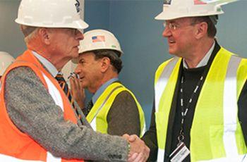 Dr. Douglas Nixon shaking hands with a man in a hard hat and orange vest