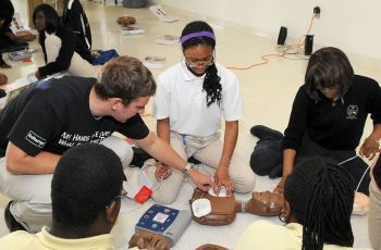Students gathered around a practice dummy to train CPR