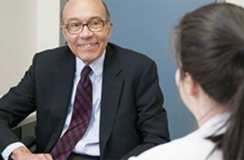 A man smiling at a student in conversation