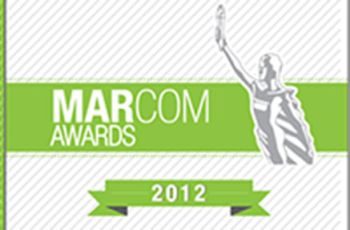 "MARCOM AWARDS 2012" | Silver figure holding a torch in front of a green banner