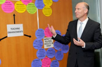 Dean Jeffrey Akman gesturing to a chart displayed on a wall