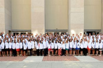 Dozens of MD students in white coats posing together
