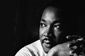 Dr. Martin Luther King, Jr. looking off to the left and clasping his hands together