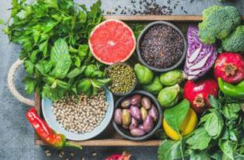 A wood tray full of many vibrant vegetables and legumes