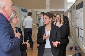 2025 Research Showcase student discussing their research with two GW faculty members