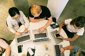 Looking down on students seated at a table collaborating on research together