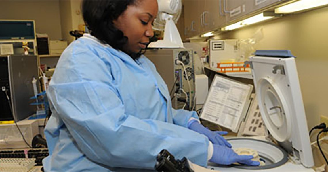 Woman in lab gear putting something into a centrifuge